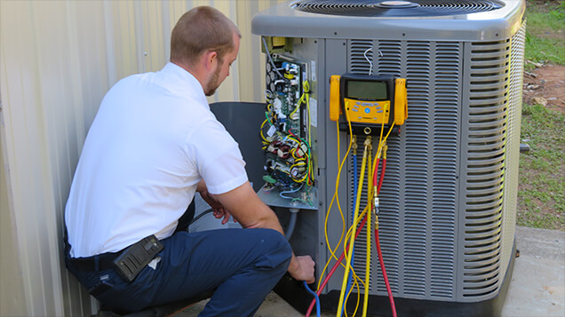 Technician verifying performance at an air conditioner service panel