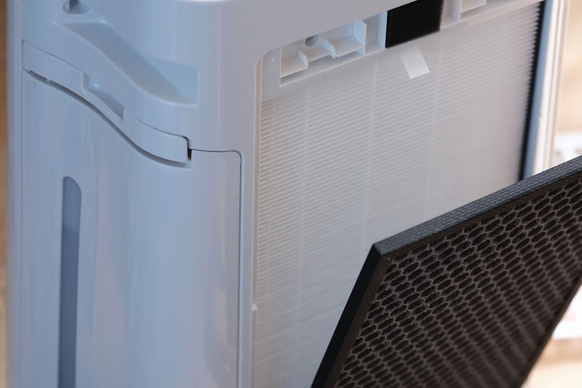 Air purifier with its cover removed showing the pleated filter and carbon filter panel