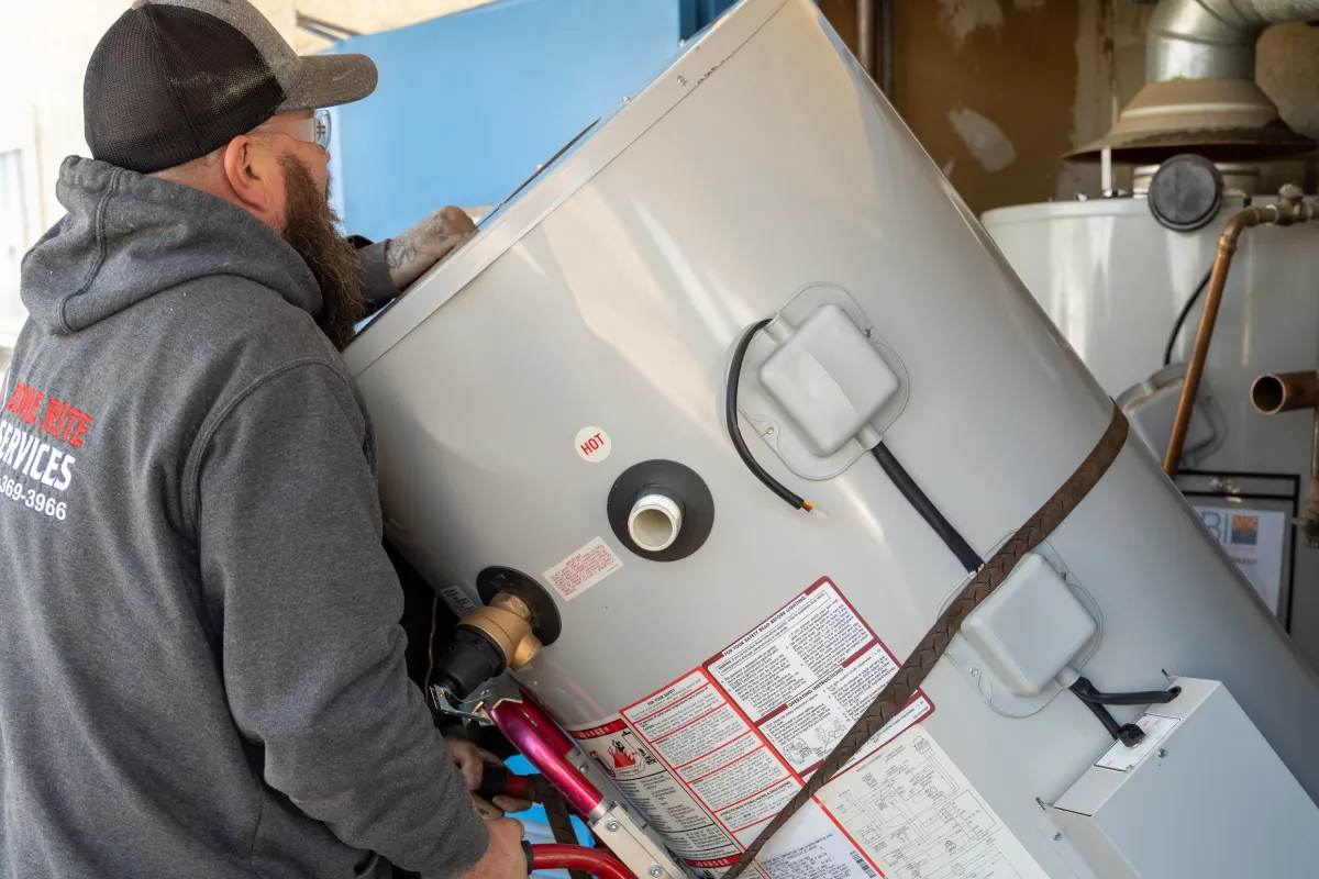 Technician in a Done Rite shirt manoeuvring a residential water heater into place
