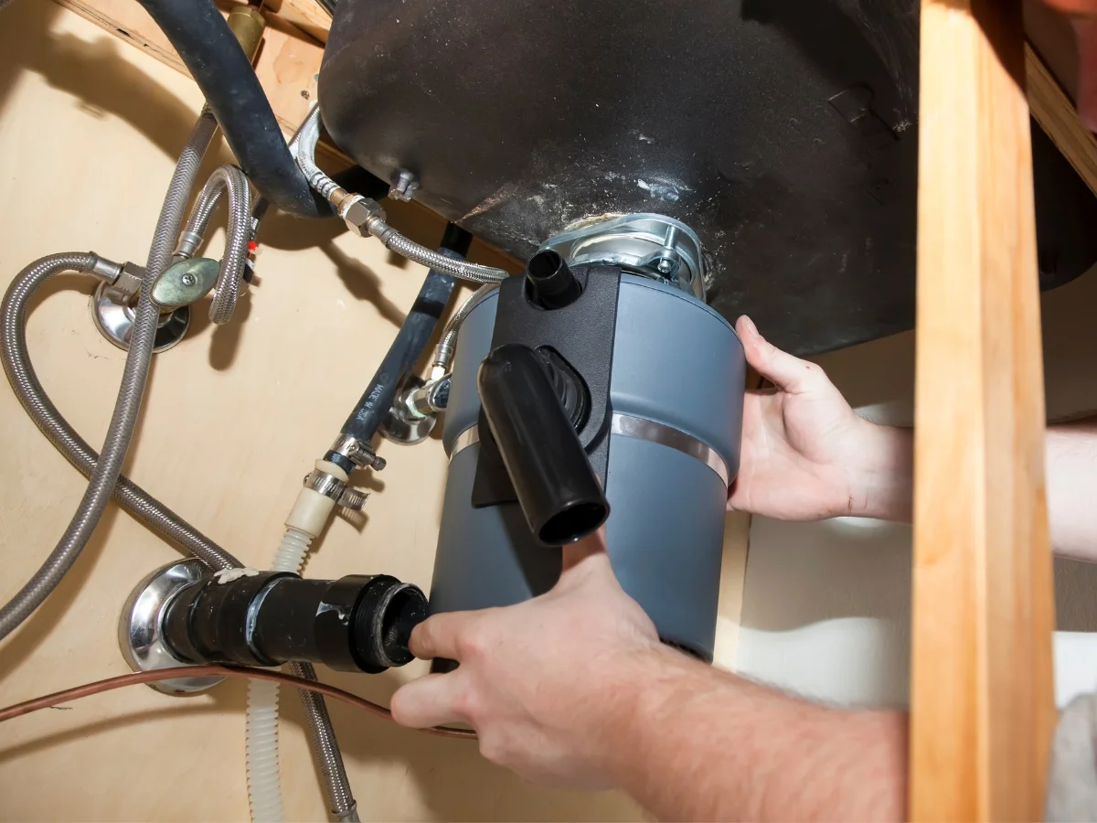 Garbage disposal being lifted into its mounting ring beneath a sink