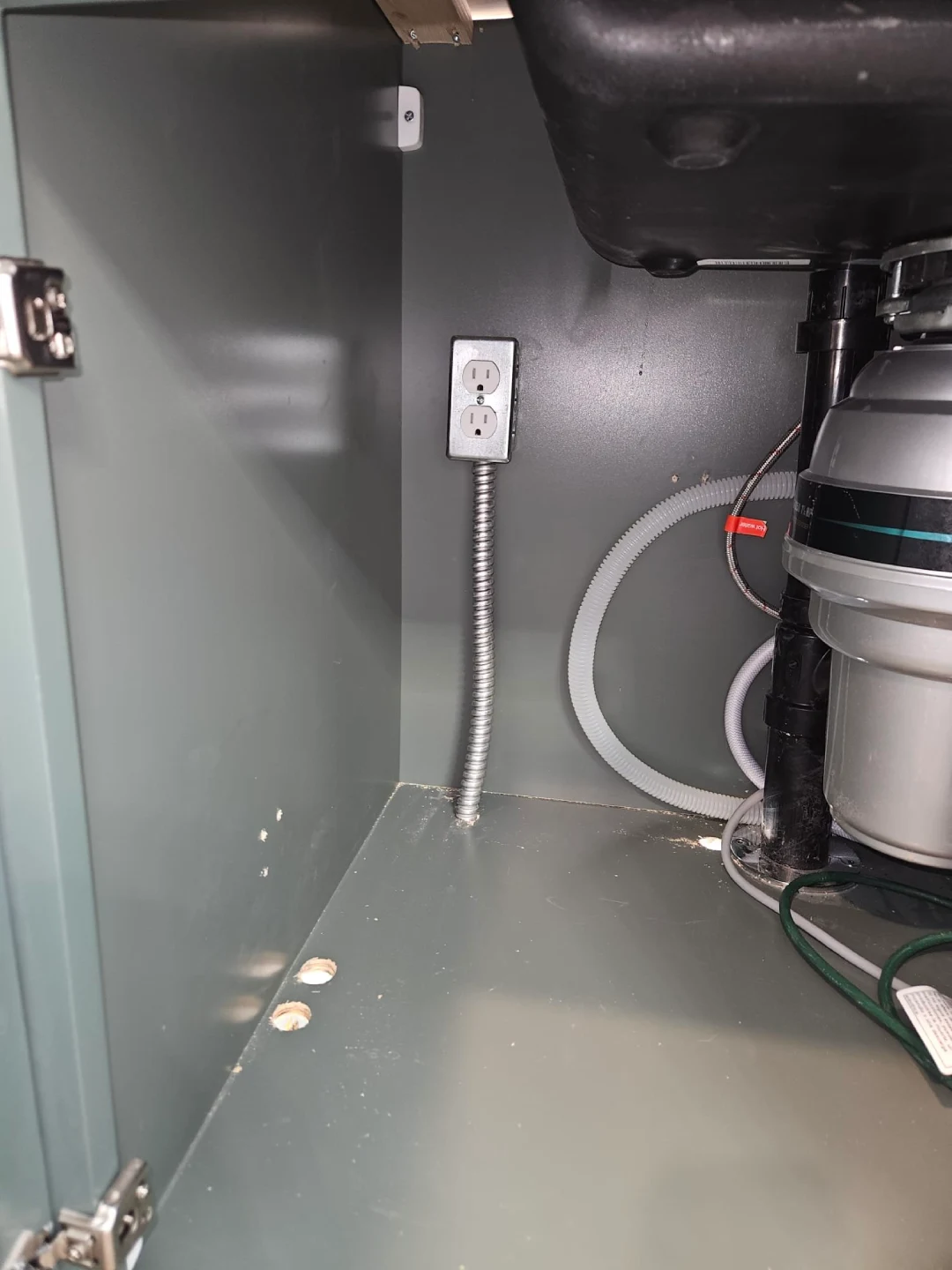 Garbage disposal, drain plumbing and electrical outlet inside a kitchen sink cabinet