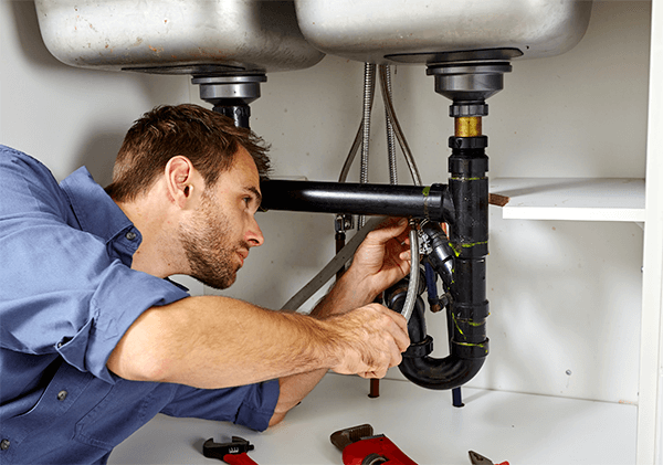 Plumber working on a blocked sink drain in a Tucson home