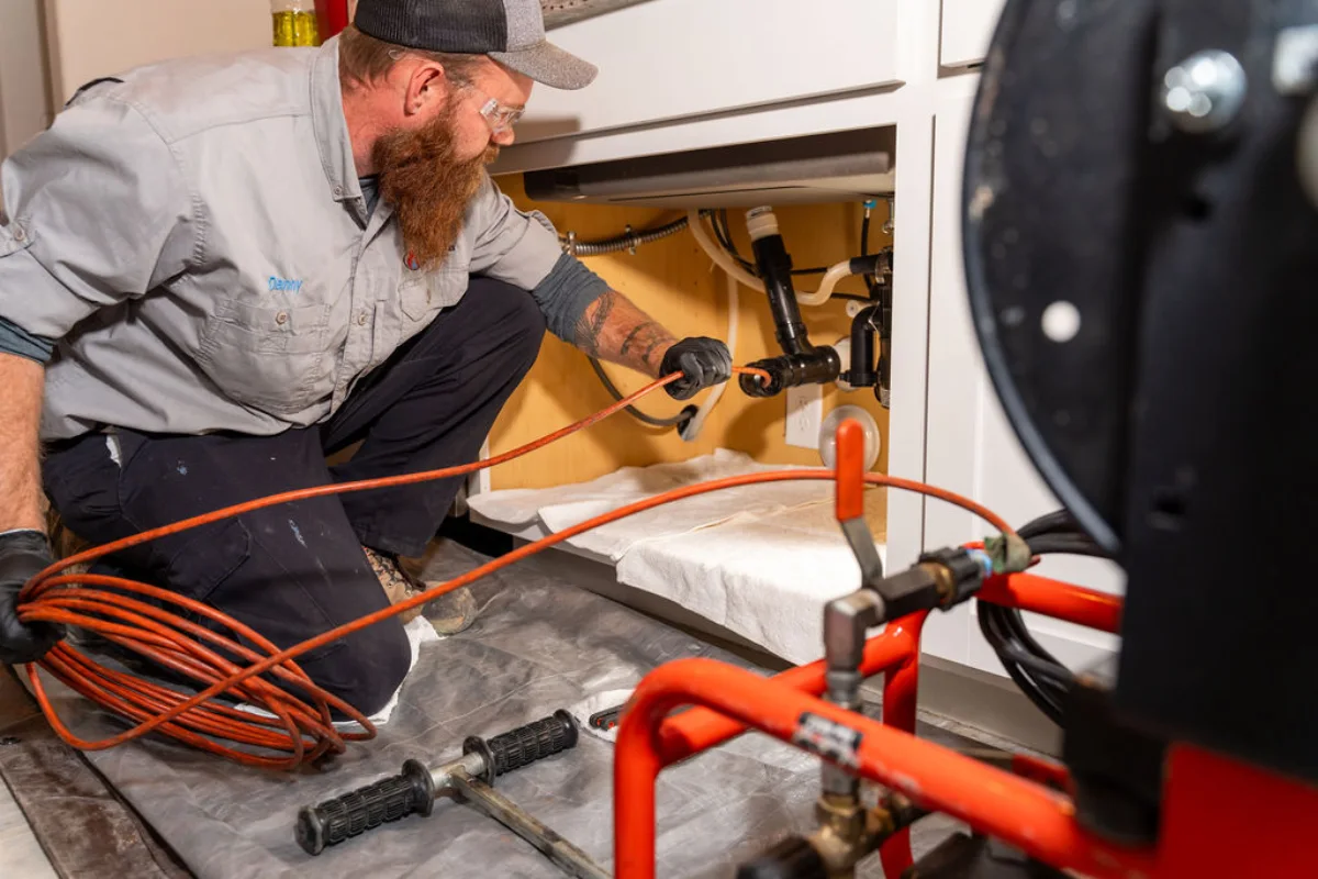 Plumber tracing a water leak under a sink in Tucson