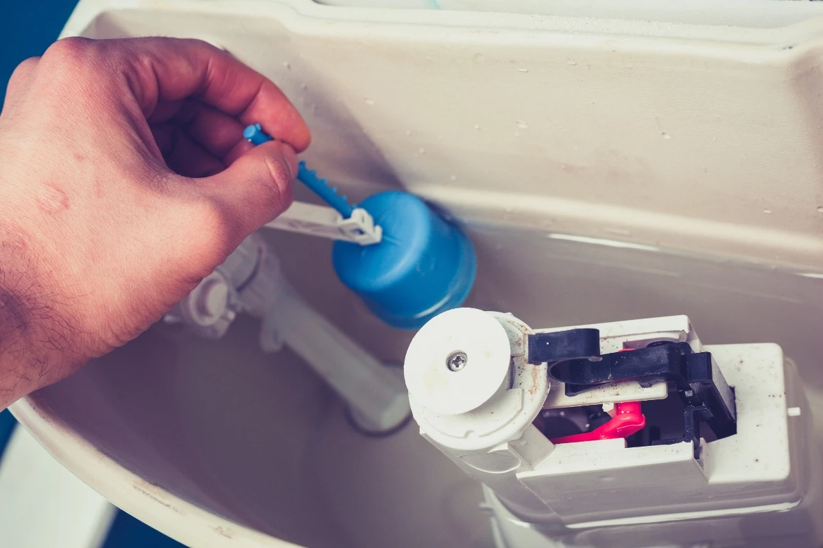 Float arm and fill valve being checked inside a toilet tank