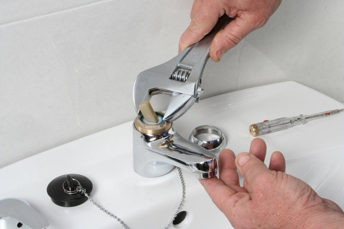 Faucet cartridge being removed from a bathroom mixer with an adjustable wrench